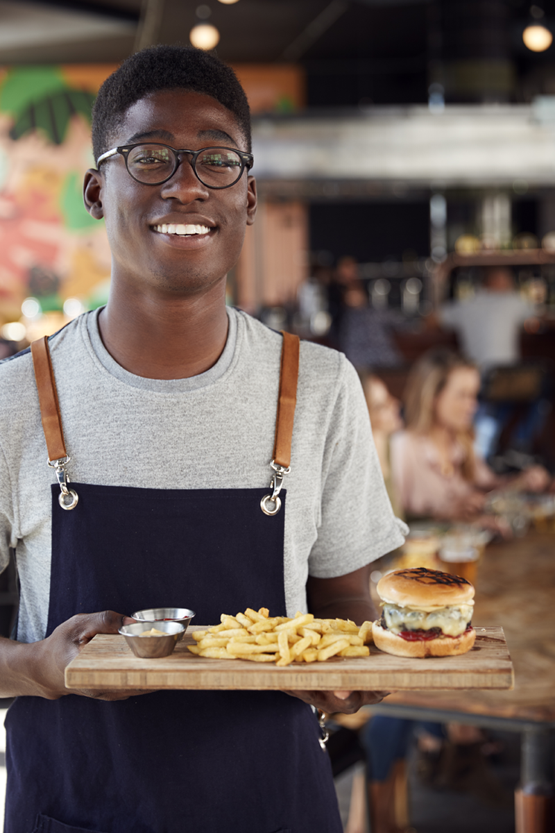 Restaurant server holding a tray with a burger and fries